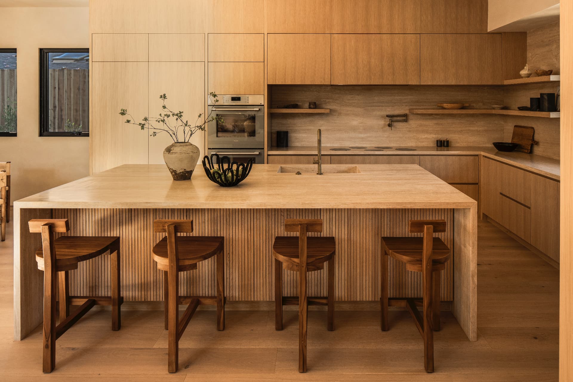 Custom kitchen with full-height oak cabinetry and a charcoal stone waterfall island