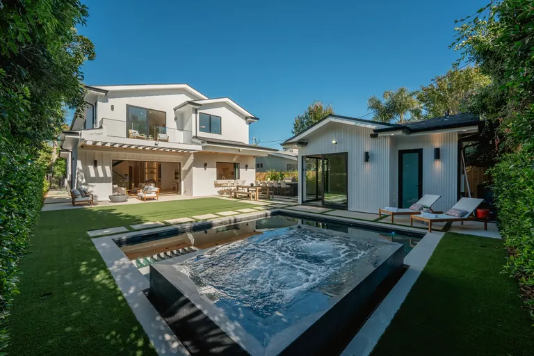 Rear yard of a Studio City home with a raised spa, pool, lawn and mature hedging