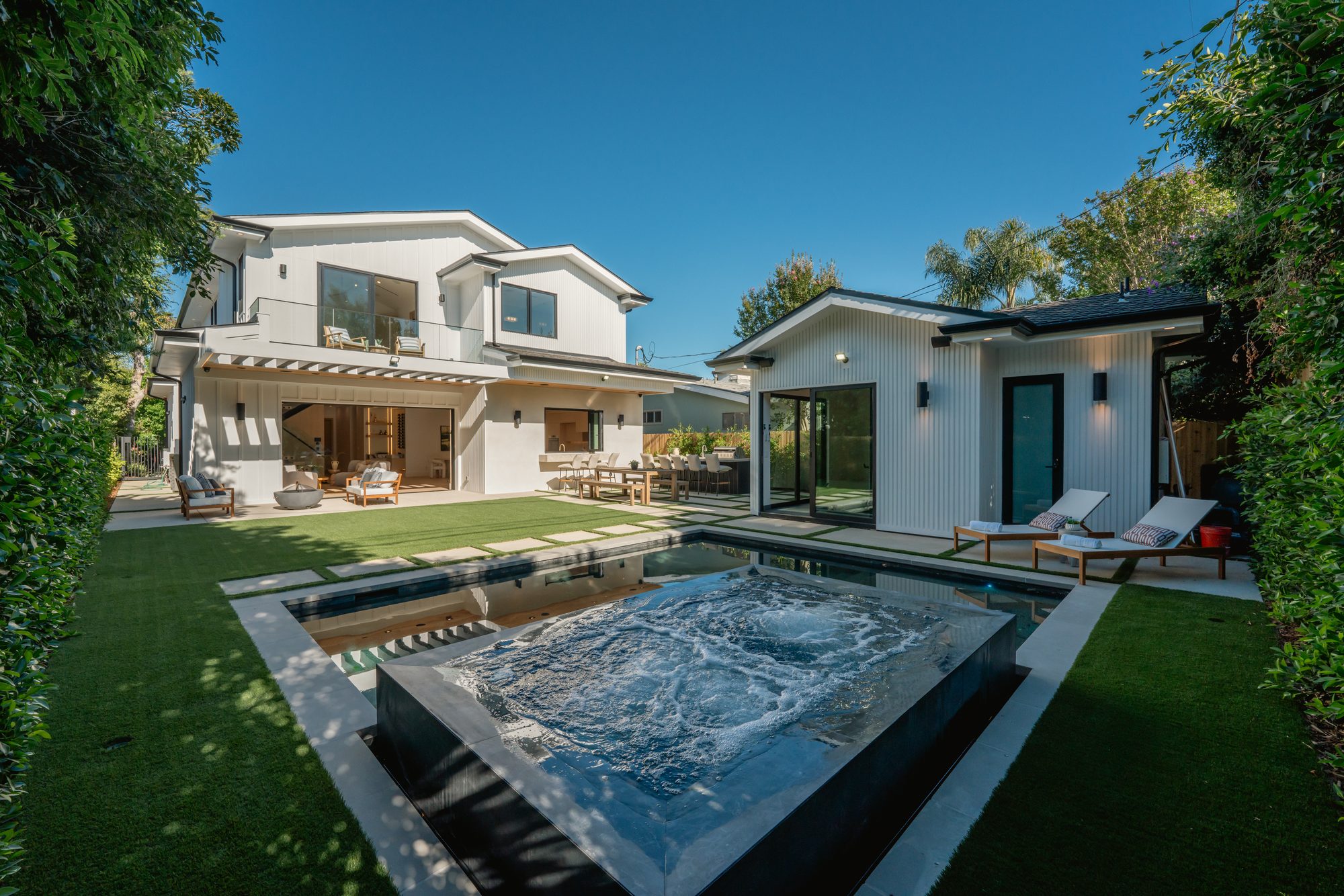 Rear yard of a Studio City home with a raised spa, pool, lawn and a covered patio off the main house