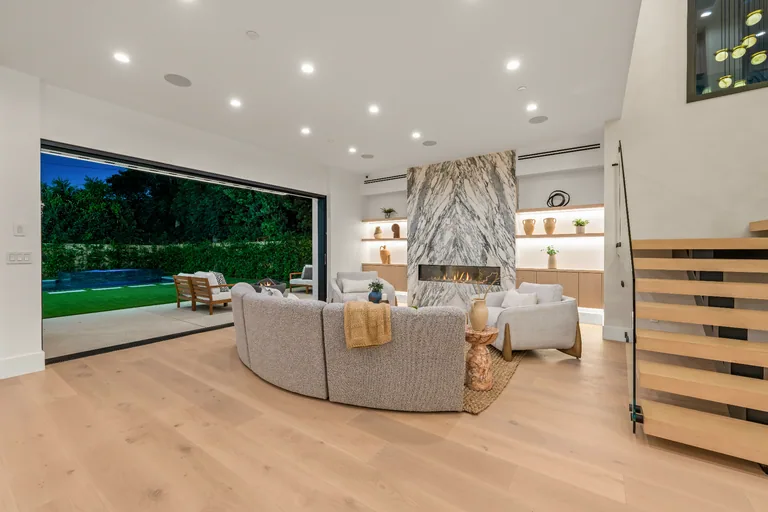 Living room with a book-matched stone fireplace and pocketing glass doors to the pool deck