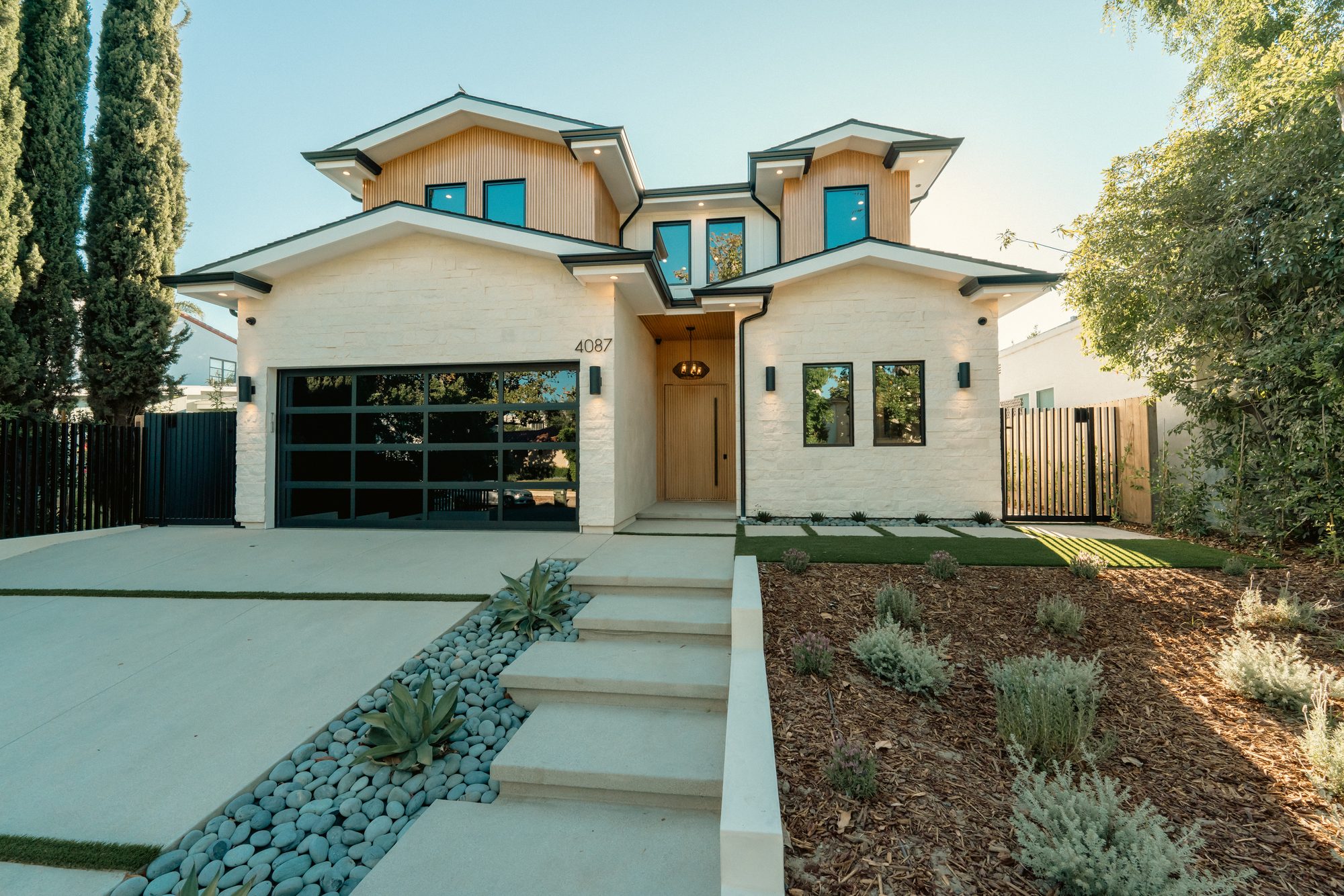 Front elevation of a custom home on Kraft Avenue in Studio City with painted brick, wood siding and a glass garage door