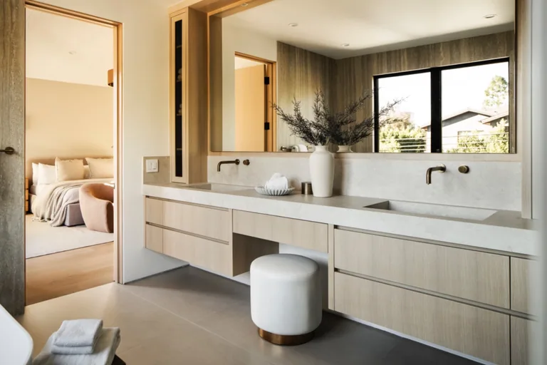 Primary bathroom with a floating double vanity, wood-framed mirror and a view through to the bedroom