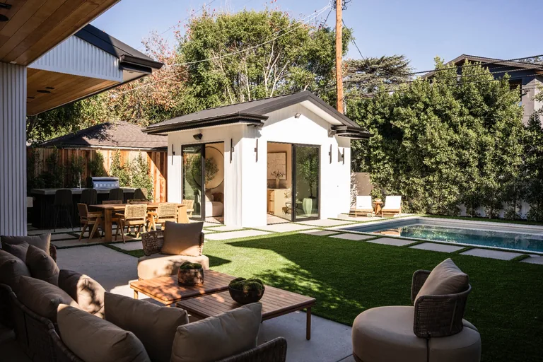 Backyard with a covered dining patio, lounge seating, lawn and a pool beside a detached cabana