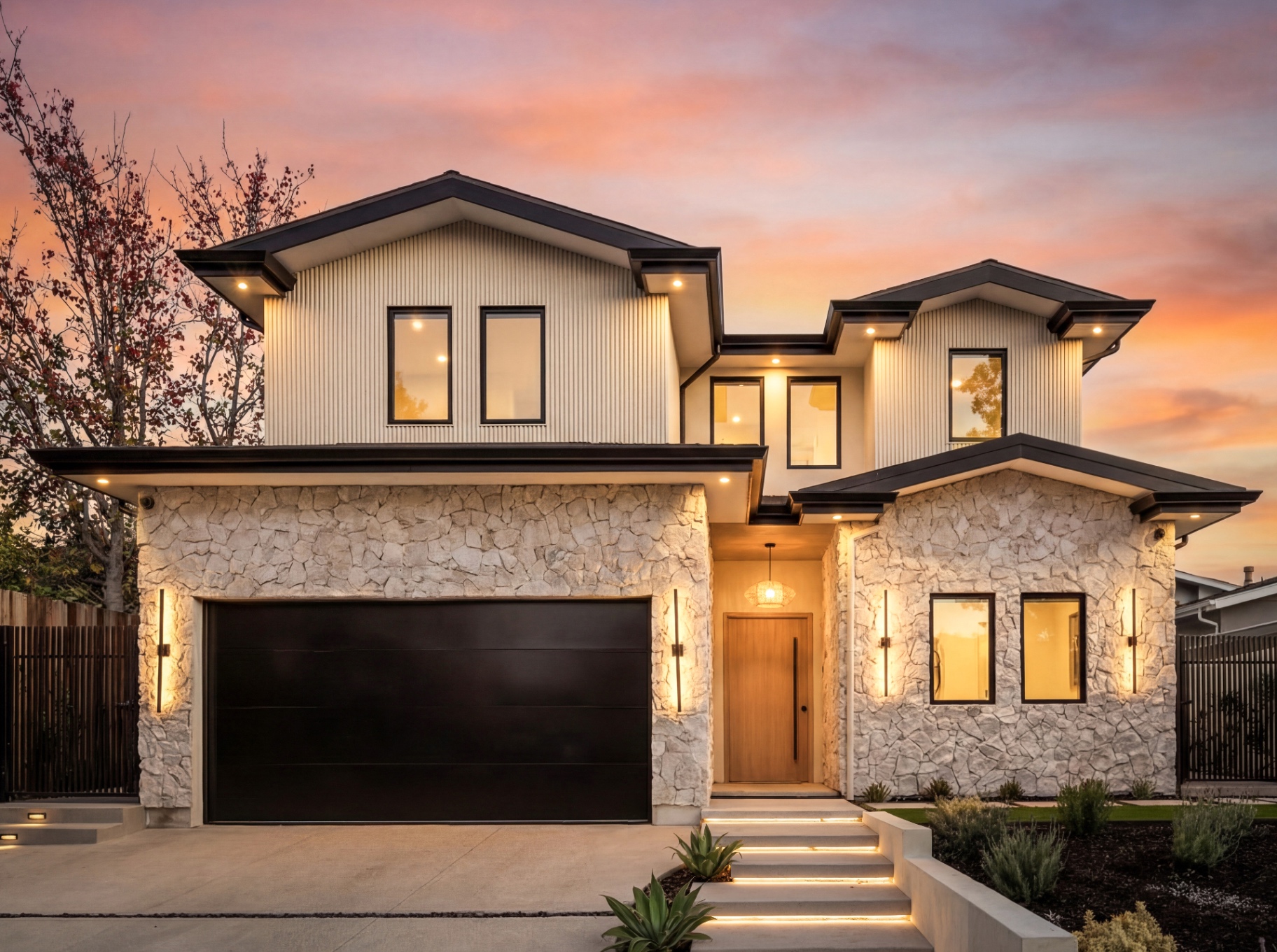 Front elevation of the new home at 4140 Kraft Ave in Colfax Meadows at sunset, with a stacked stone base, board-and-batten siding and a black garage door