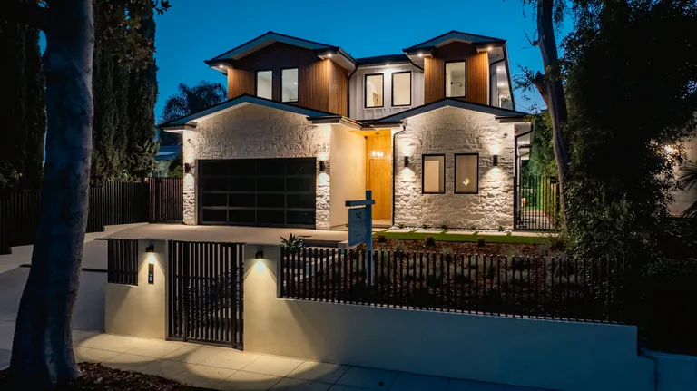 Evening exterior of the new home at 4087 Kraft Ave in Studio City, with stacked stone, vertical wood siding and warm architectural lighting