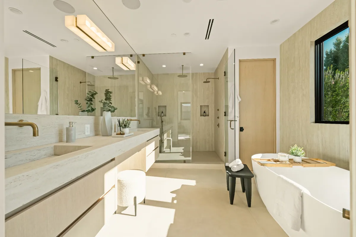 Primary bathroom with a long stone vanity, freestanding soaking tub and a glass-enclosed walk-in shower