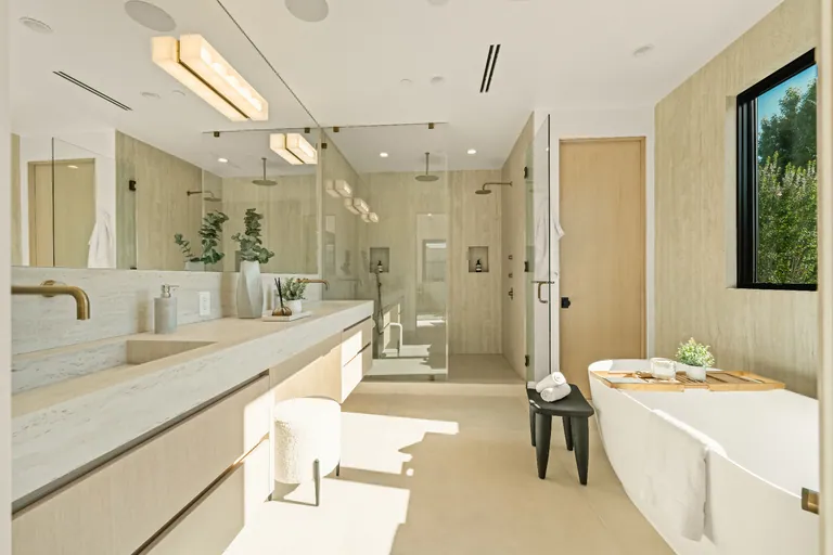 Primary bathroom with a long stone vanity, freestanding soaking tub and a glass-enclosed walk-in shower