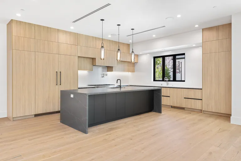 Custom kitchen with full-height oak cabinetry and a charcoal stone waterfall island