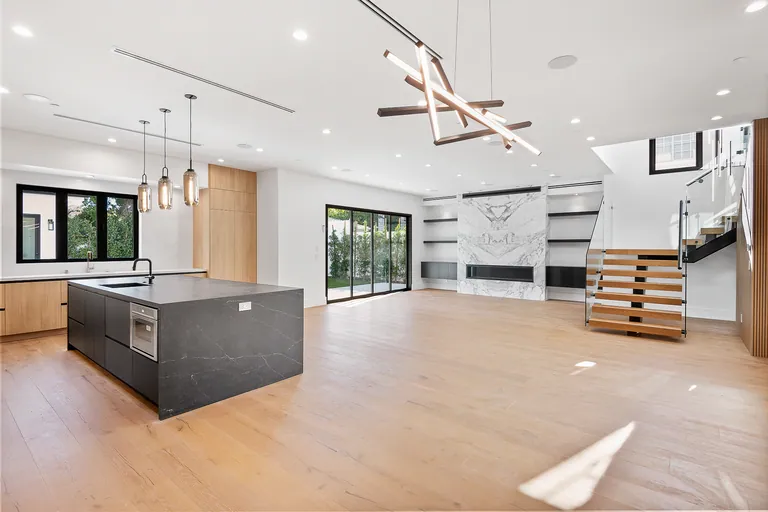 Great room with a marble fireplace wall, open kitchen with waterfall island and a floating wood staircase