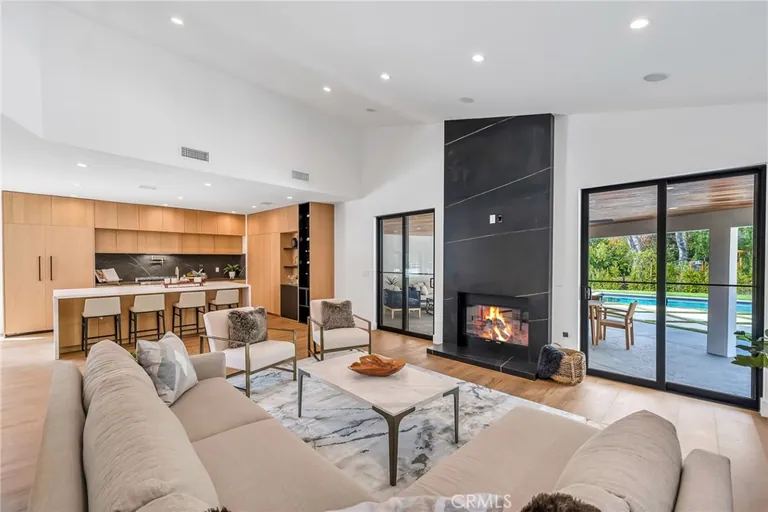 Living room with sectional seating, a full-height black stone fireplace and sliding doors to the pool